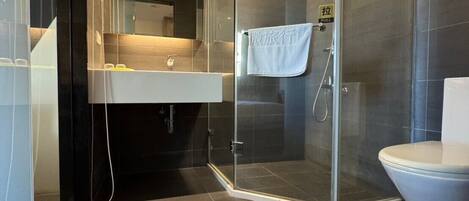 Un baño moderno con ducha de vidrio, inodoro blanco y tocador con espejo.