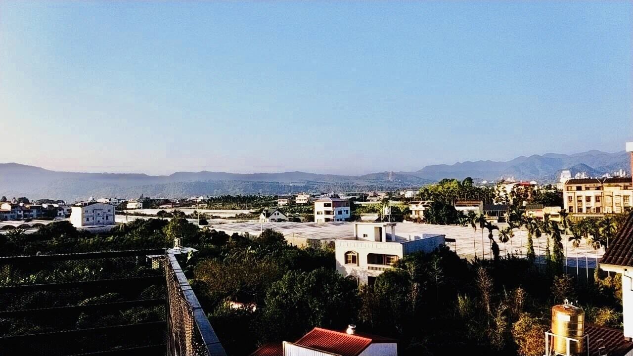 Un quartiere residenziale con case, un ponte e montagne sullo sfondo.