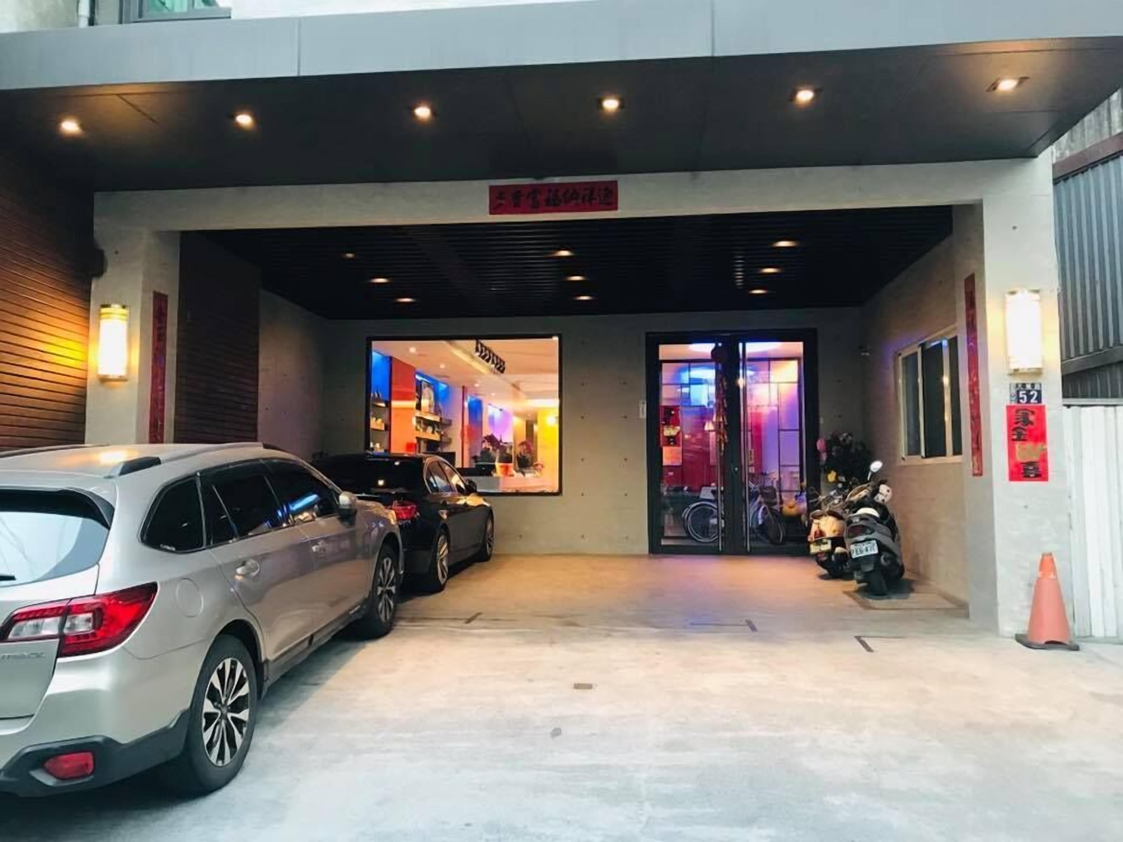 Un área de estacionamiento con dos coches aparcados frente a un edificio con entrada de vidrio.