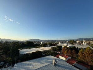 Terrat amb antena parabòlica, envoltat d'edificis i arbres, sota un cel serè.