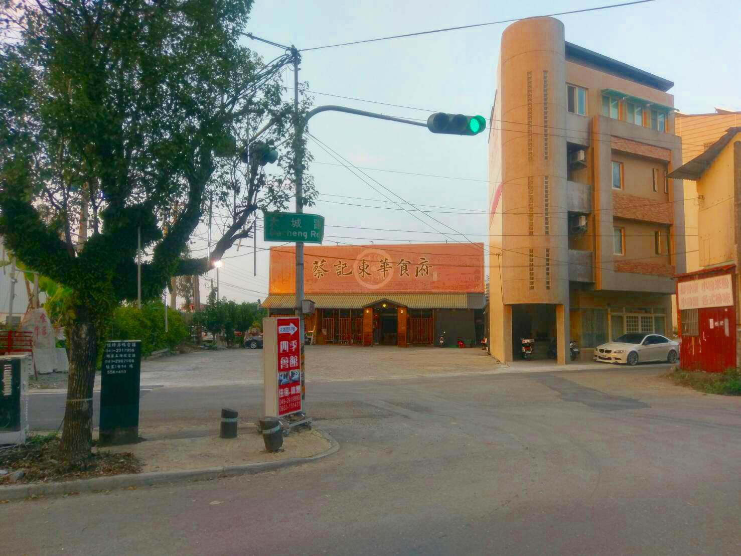 A street corner with a traffic light, a building with a sign reading "City Restaurant," and a tree.