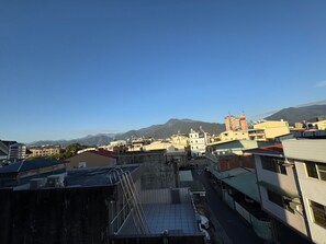 A cityscape with buildings, a clear sky, and mountains in the background. - Travel Light Hotel (Puli)