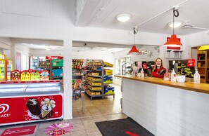 A brightly lit convenience store with a variety of products on shelves and a Coca-Cola refrigerator.