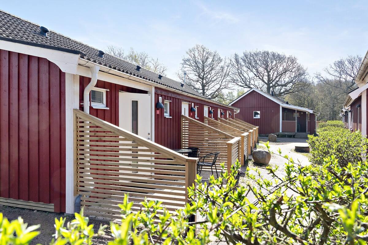 A row of red wooden cabins with wooden railings and a gravel path.
