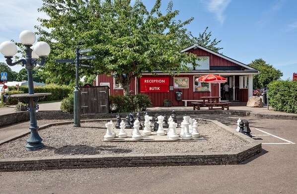 A reception area with a chessboard outside, a red building, and a parking lot.