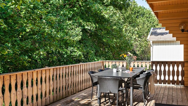 Eine Terrasse im Freien mit Holzdeck, einem Tisch mit Stühlen und einem Blumentopf.