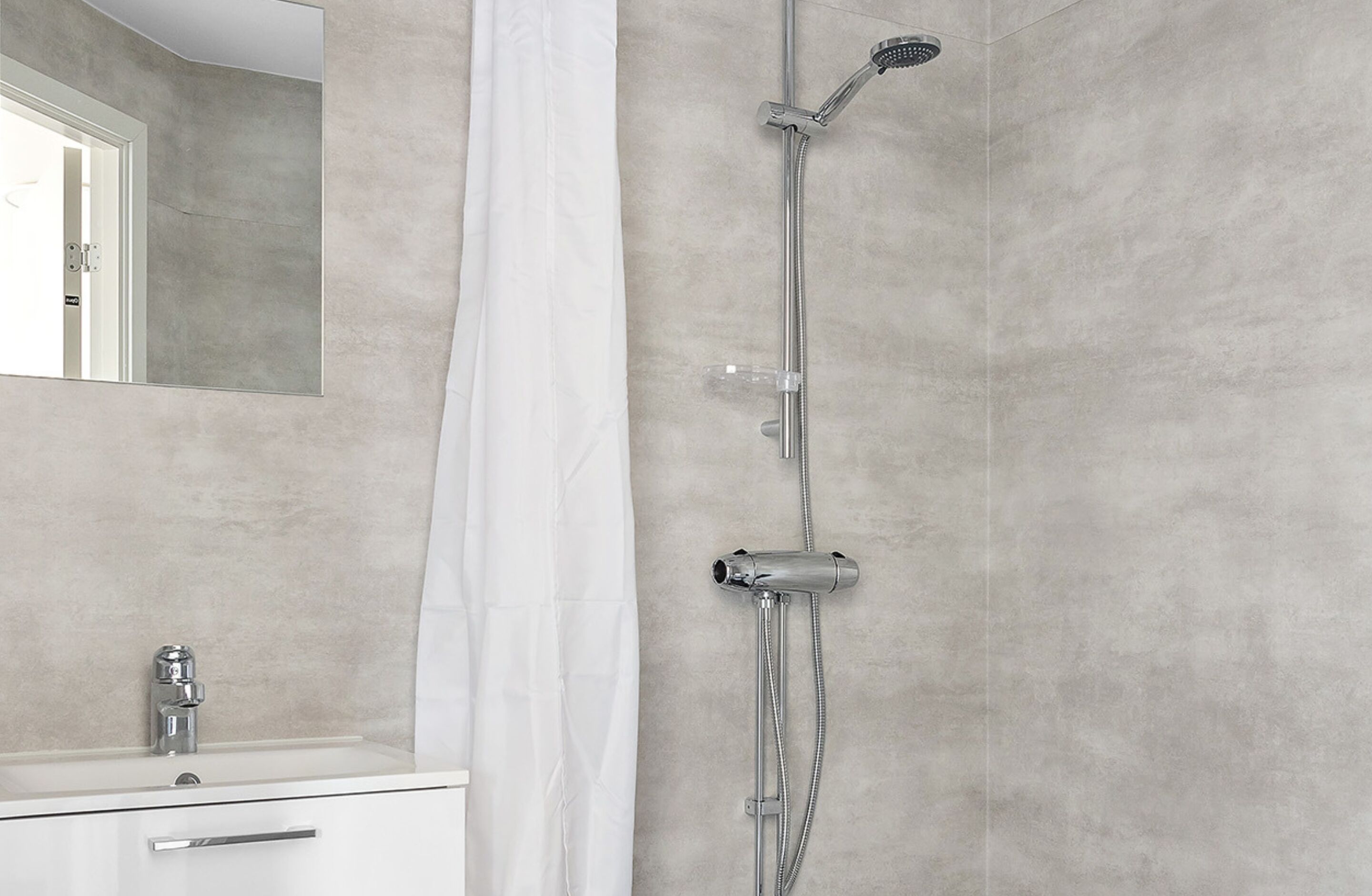 Un baño con ducha, lavamanos y espejo.