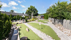 Ein Minigolfplatz mit Kiesweg, grünem Rasen und nummerierten Bahnen.