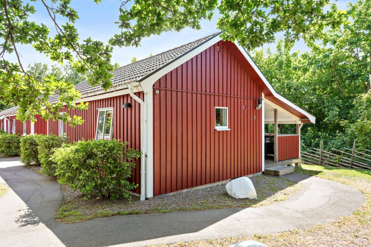 A red barn-style building with a sloped roof, a small porch, and a gravel driveway.