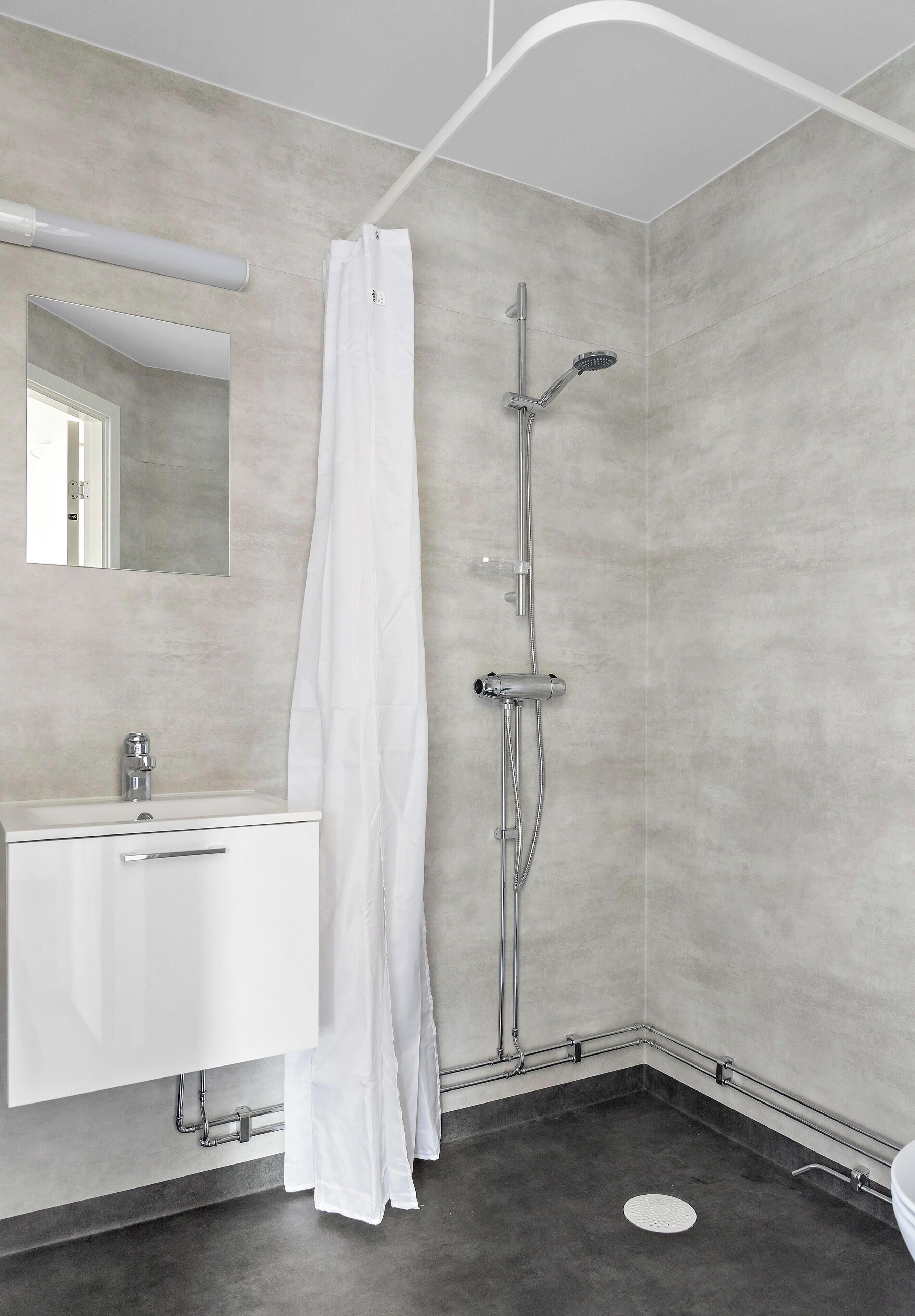 A modern bathroom with a shower, a sink, and a mirror.