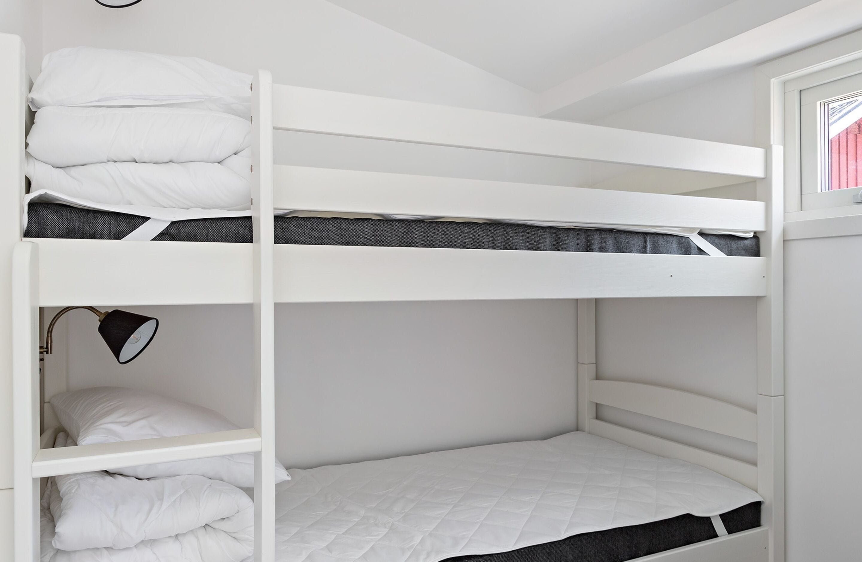 A bunk bed room with a desk and a lamp.