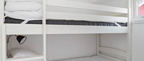 A bunk bed room with a desk and a lamp.