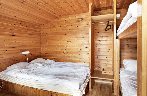 A wooden cabin room with a bunk bed, a bedside table, and a hanging light fixture. - First Camp Mölle (Nyhamnslage)