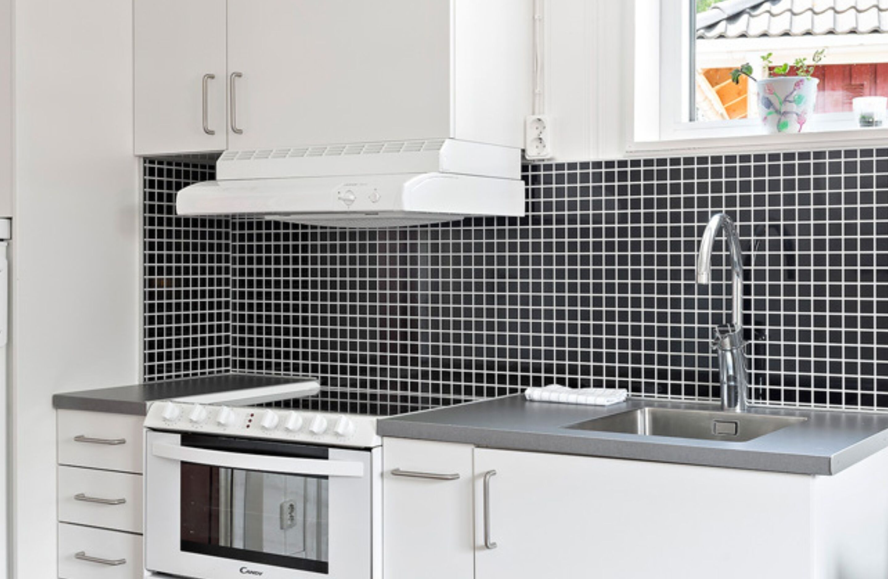 Una cocina con armarios blancos, una estufa y un lavabo.