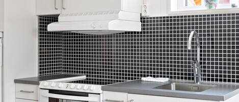 Una cocina con armarios blancos, una estufa y un lavabo.
