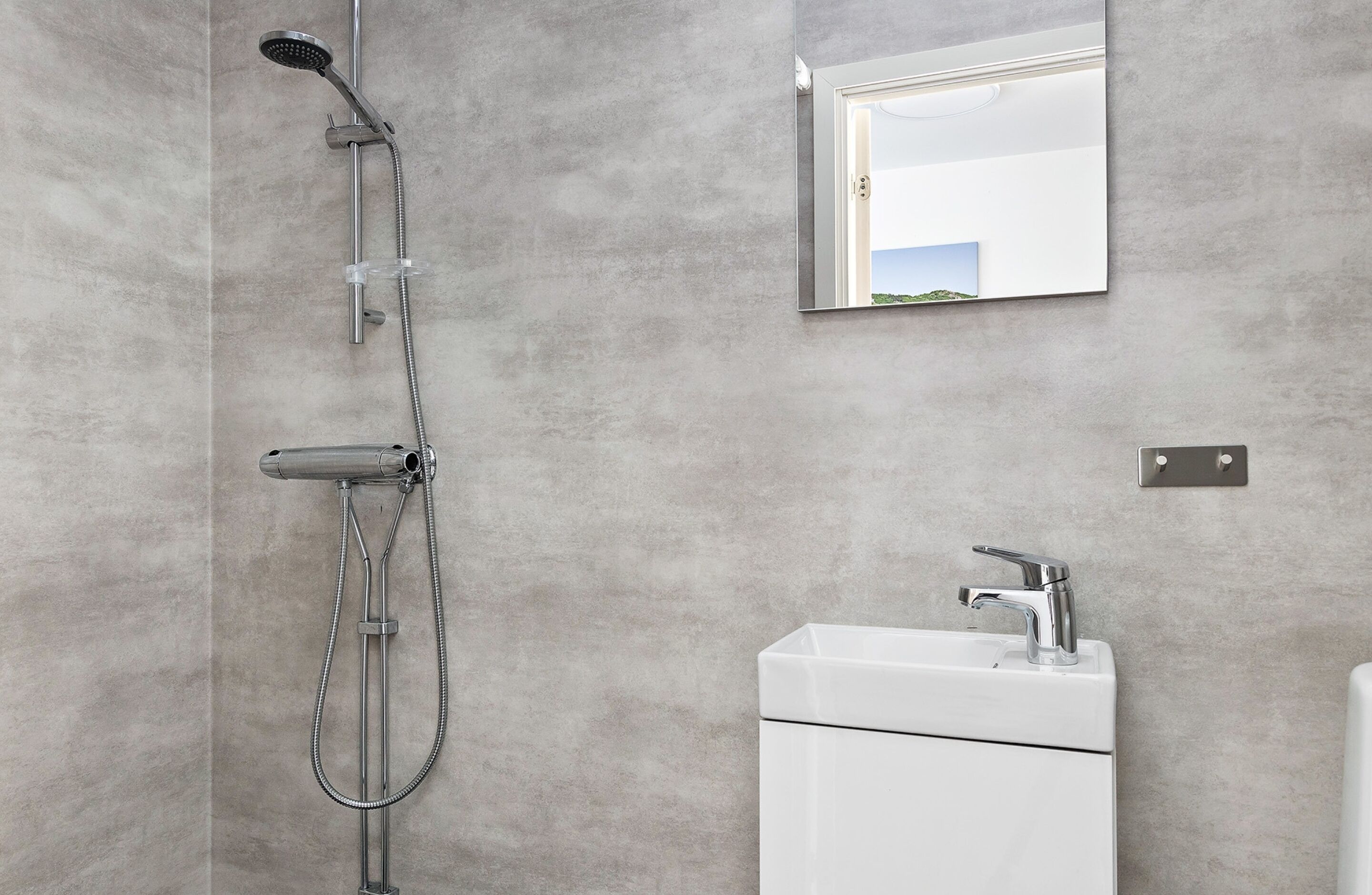 A modern bathroom with a shower, sink, and mirror.