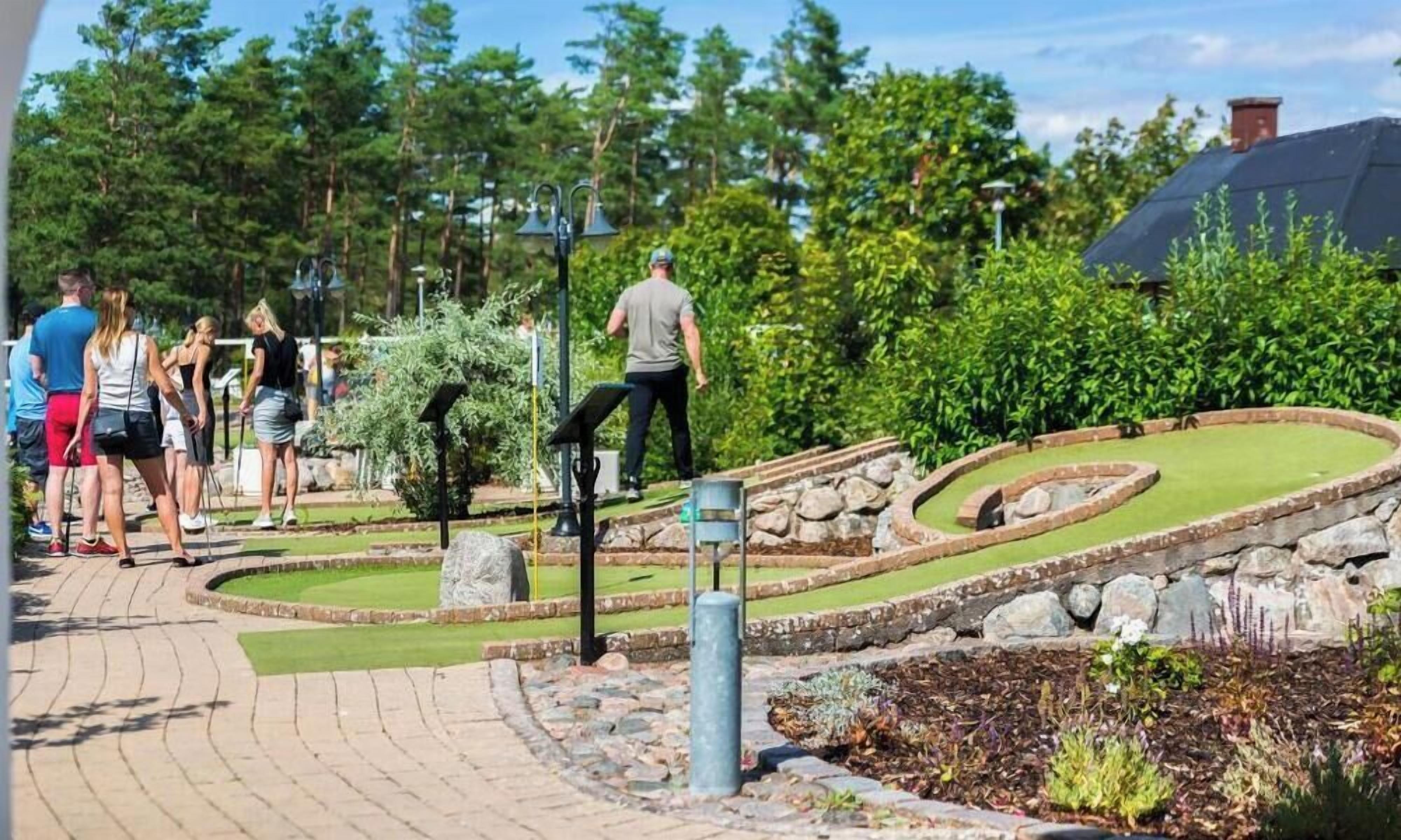Un área ajardinada con un sendero sinuoso, un pequeño jardín y un edificio al fondo.