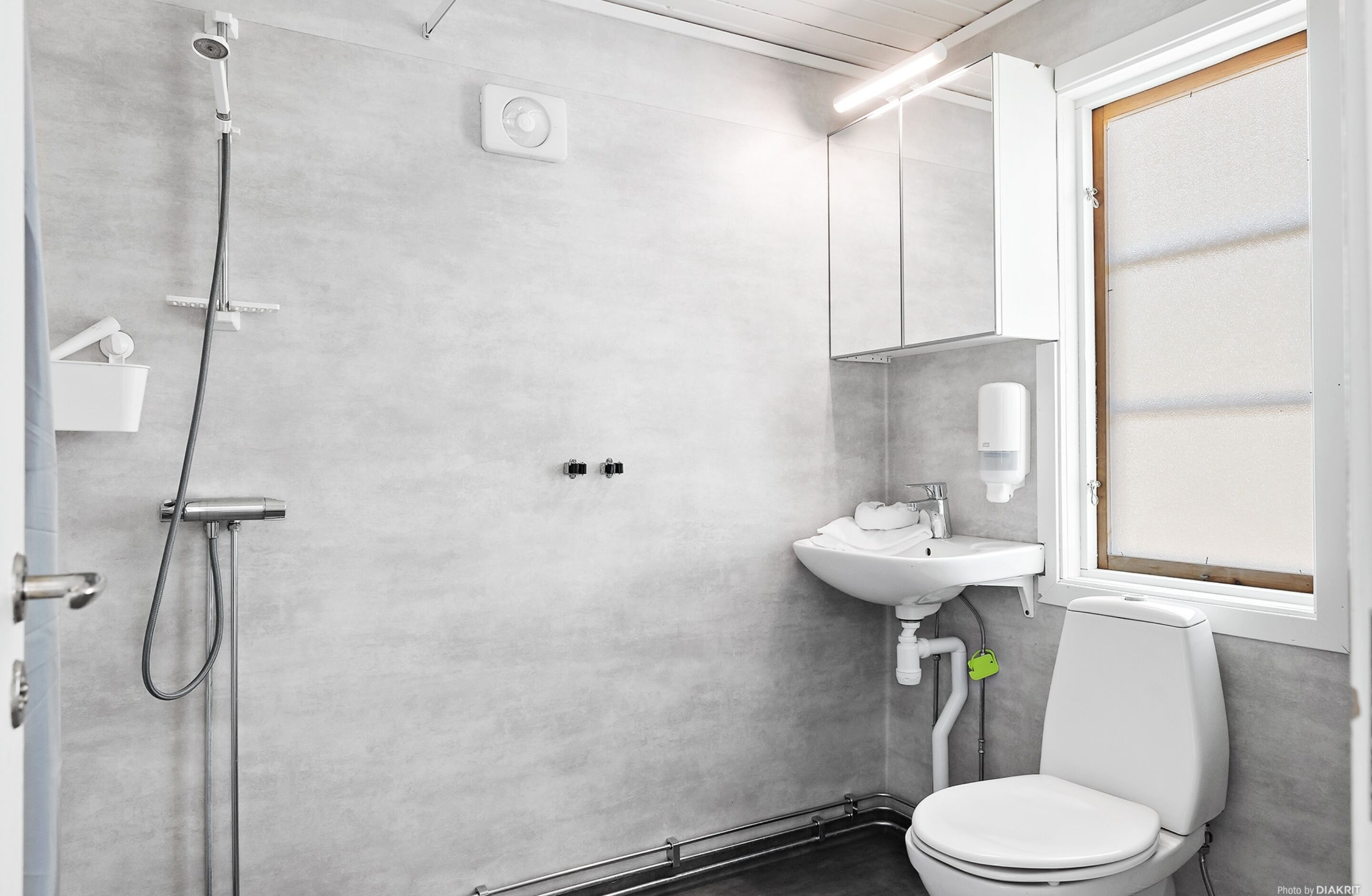 A modern bathroom with a shower, sink, and toilet.