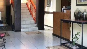 A hotel lobby with a staircase, a reception desk, and a potted plant. - Herbies Mansion (Olongapo)