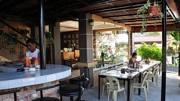 An outdoor dining area with a bar, chairs, and a counter. - Herbies Mansion (Olongapo)