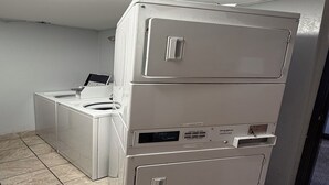 A stacked washer and dryer unit in a laundry room with a digital display and control panel. -  Coratel Inn and Suites by Jasper Stillwater (Stillwater)