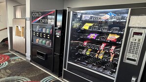 A vending machine area with a cold drink machine and a snack vending machine. -  Coratel Inn and Suites by Jasper Stillwater (Stillwater)