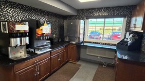 A kitchen with a coffee station, a microwave, and a window with a view of parked cars. -  Coratel Inn and Suites by Jasper Stillwater (Stillwater)