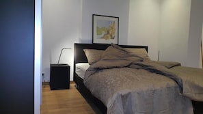 A bedroom with a bed, a nightstand, a lamp, and a framed picture on the wall. - Mansion 6 (Maastricht)
