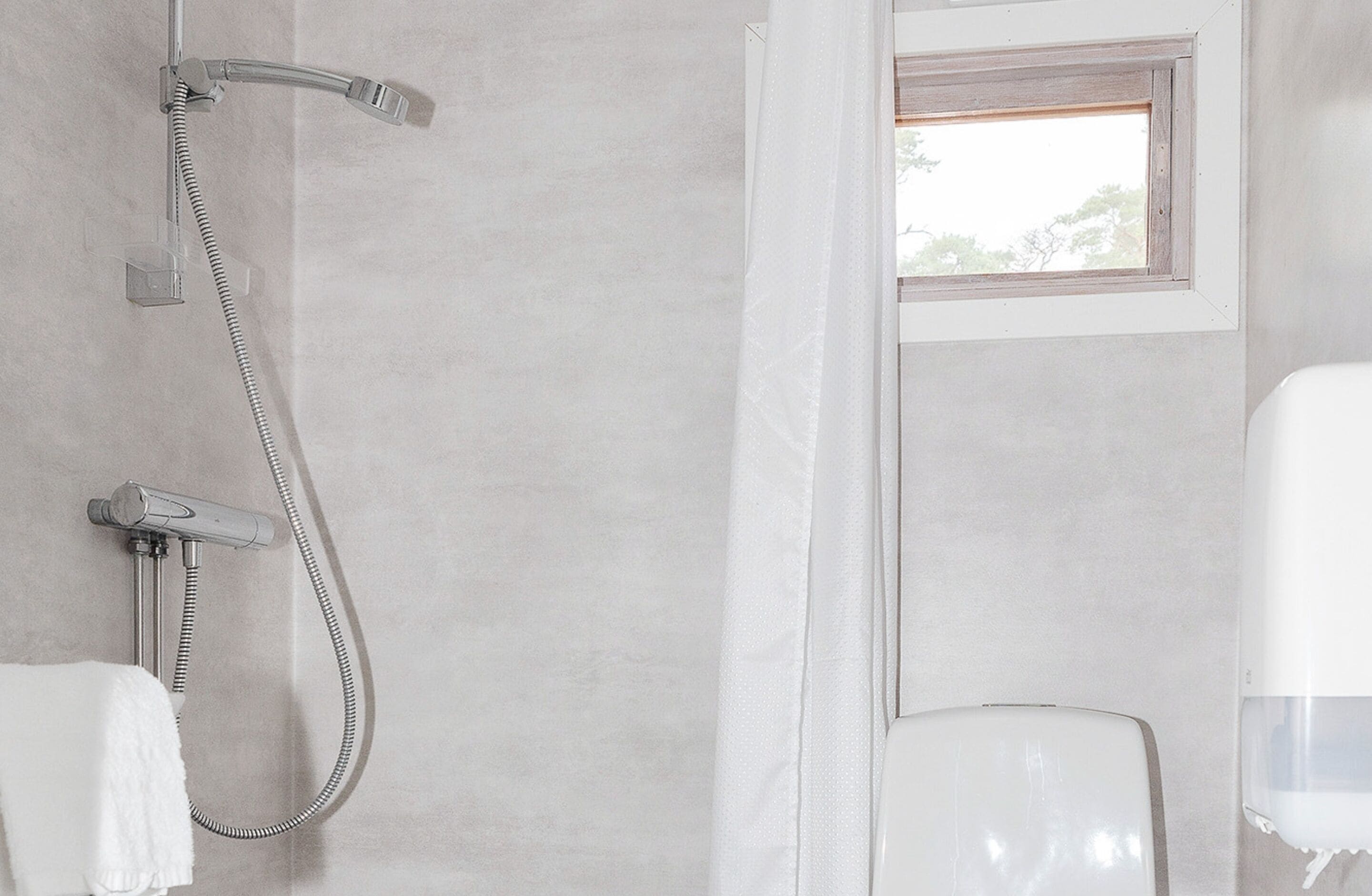 A bathroom with a shower, a window, and a toilet.