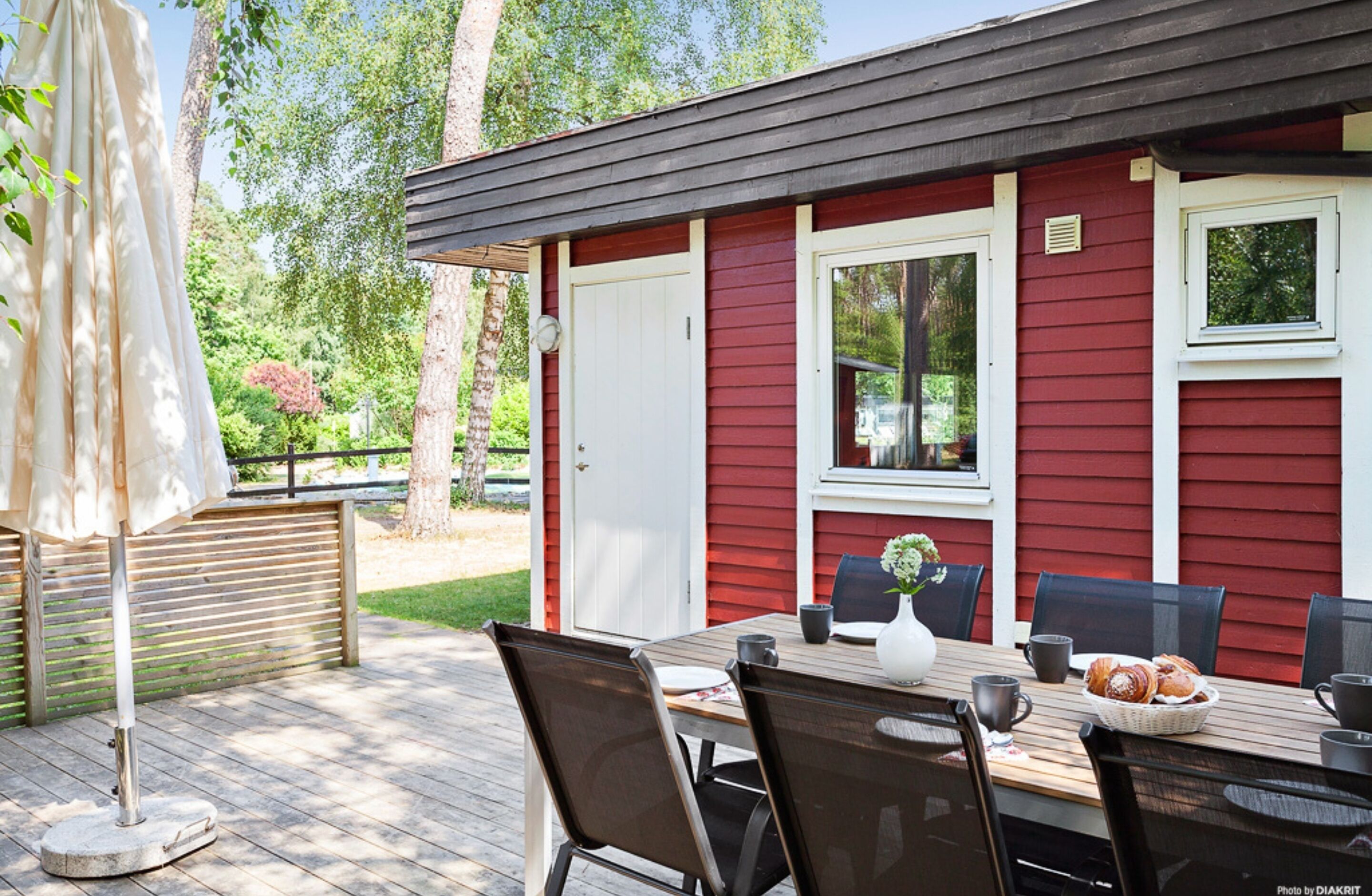 Een rood-wit gebouw met een terras, zitplaatsen buiten en een gedekte tafel.