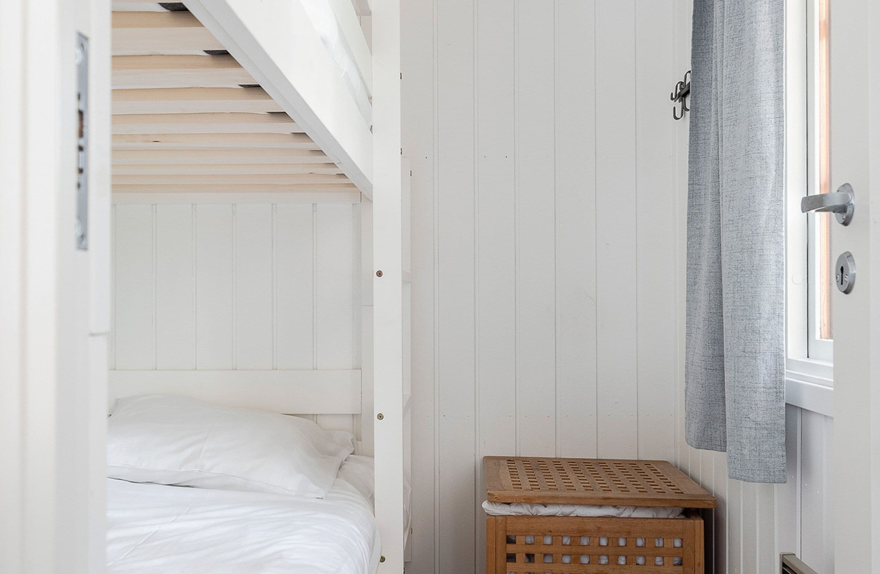 Ein Schlafzimmer mit einem Etagenbett, einer Holzkiste und einem Fenster mit Vorhängen.