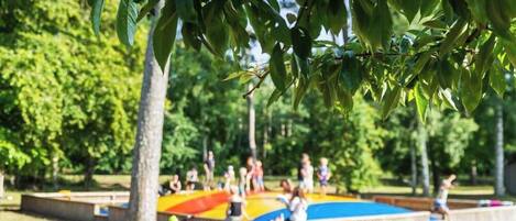 Un parque infantil con una estructura de juegos colorida y un árbol al frente.
