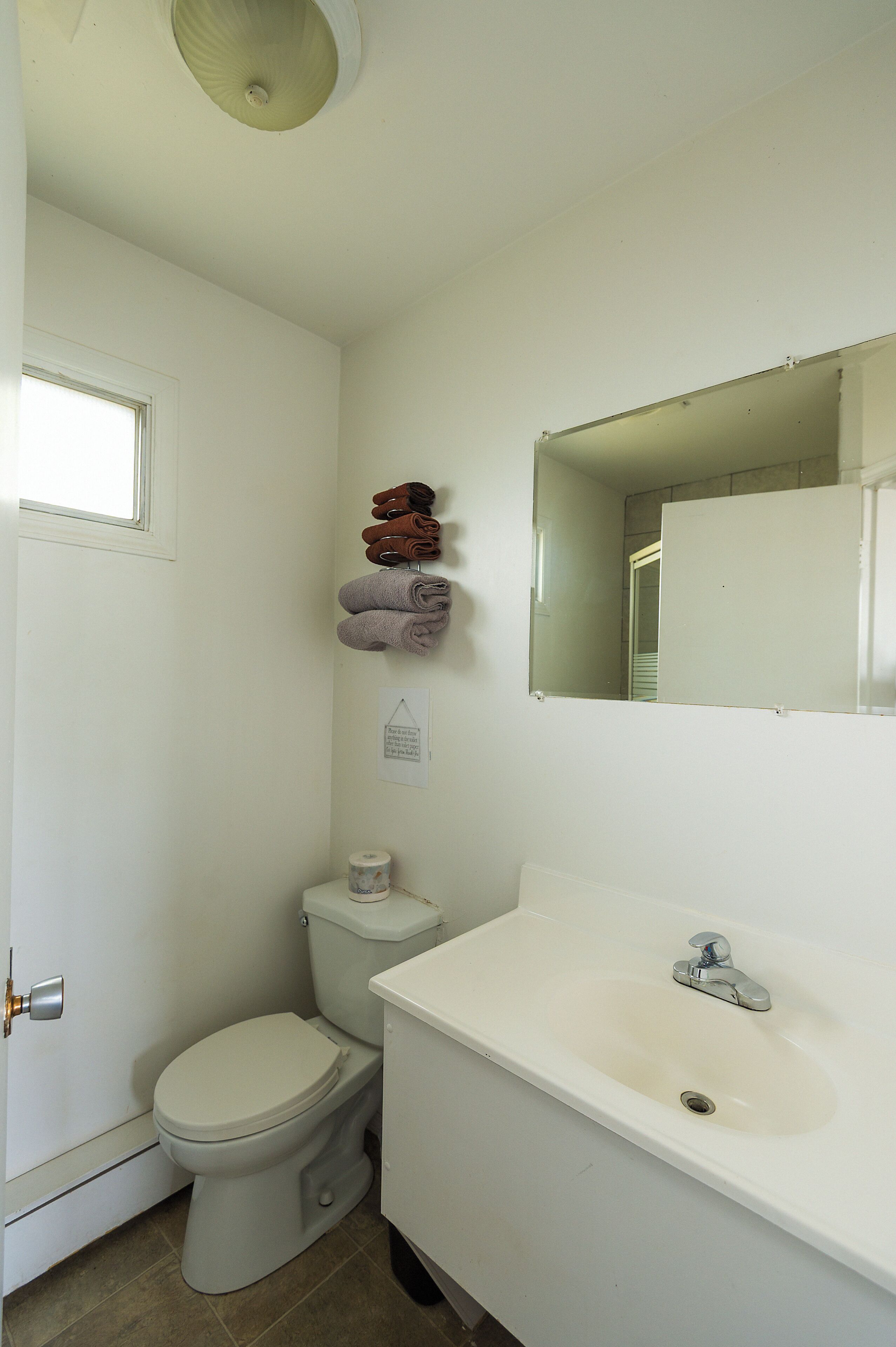 A bathroom with a toilet, sink, and towels on a rack.