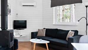 A modern living room with a black sofa, white coffee table, and a TV on a white stand.