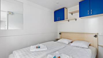 Ett hotellrum med en säng, två blå skåp, en spegel och en liten hylla.