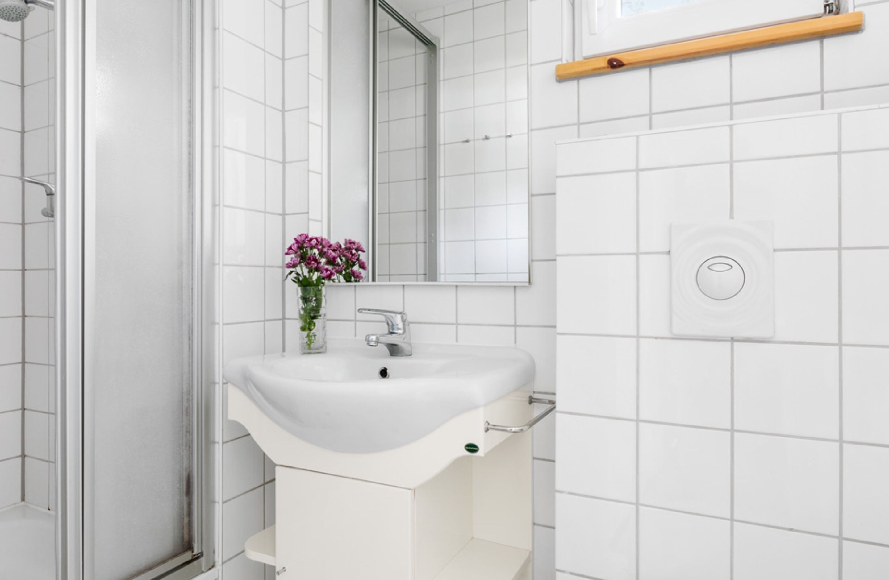 A bathroom with a white sink, a mirror, and a shower.