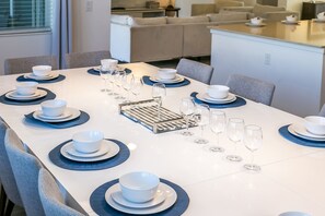 A dining table set with white bowls and plates, glasses, and a tray. - Sonoma Resort (Kissimmee)