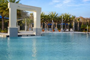A pool with a modern water feature, surrounded by palm trees and lounge chairs. - Sonoma Resort (Kissimmee)