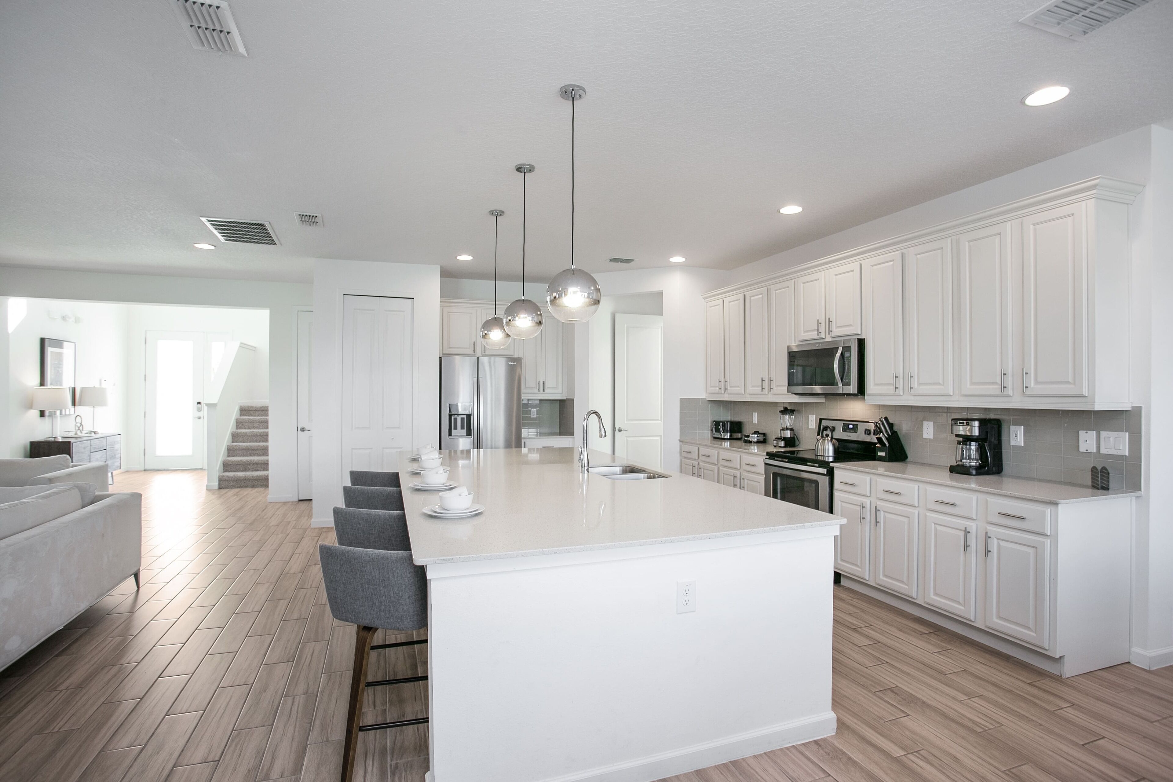 A modern kitchen with white cabinetry, a central island, and pendant lighting.