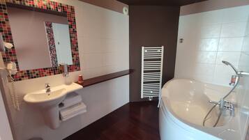 A modern bathroom with a white sink, mirror, and bathtub.