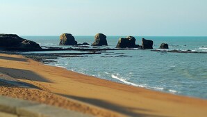 A beach with rocky formations and a clear sky.