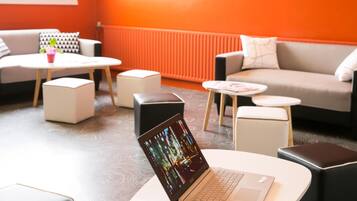 Un área de descanso moderna con una laptop sobre una mesa, un sofá y una mesita de centro.