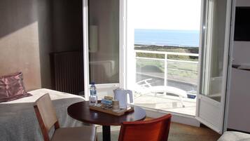 A hotel room with a balcony, a bed, a table with a tray, and a chair.