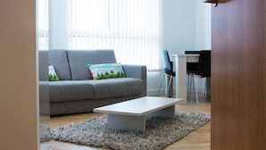 A modern living room with a grey sofa, a white coffee table, and a wooden door. - Rethink Living - Hewitt Tower (Reading)