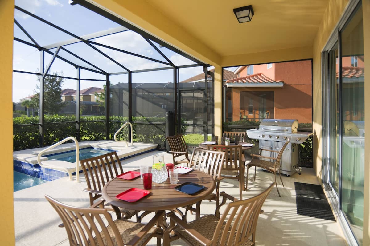 A covered patio with a pool, outdoor grill, and dining area.