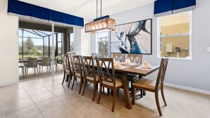 A dining area with a large table, chairs, and a hanging light fixture. - Solterra Resort (Davenport)