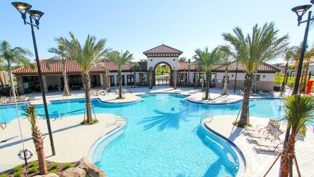 A resort pool area with multiple pools, palm trees, and lounge chairs. - Solterra Resort (Davenport)