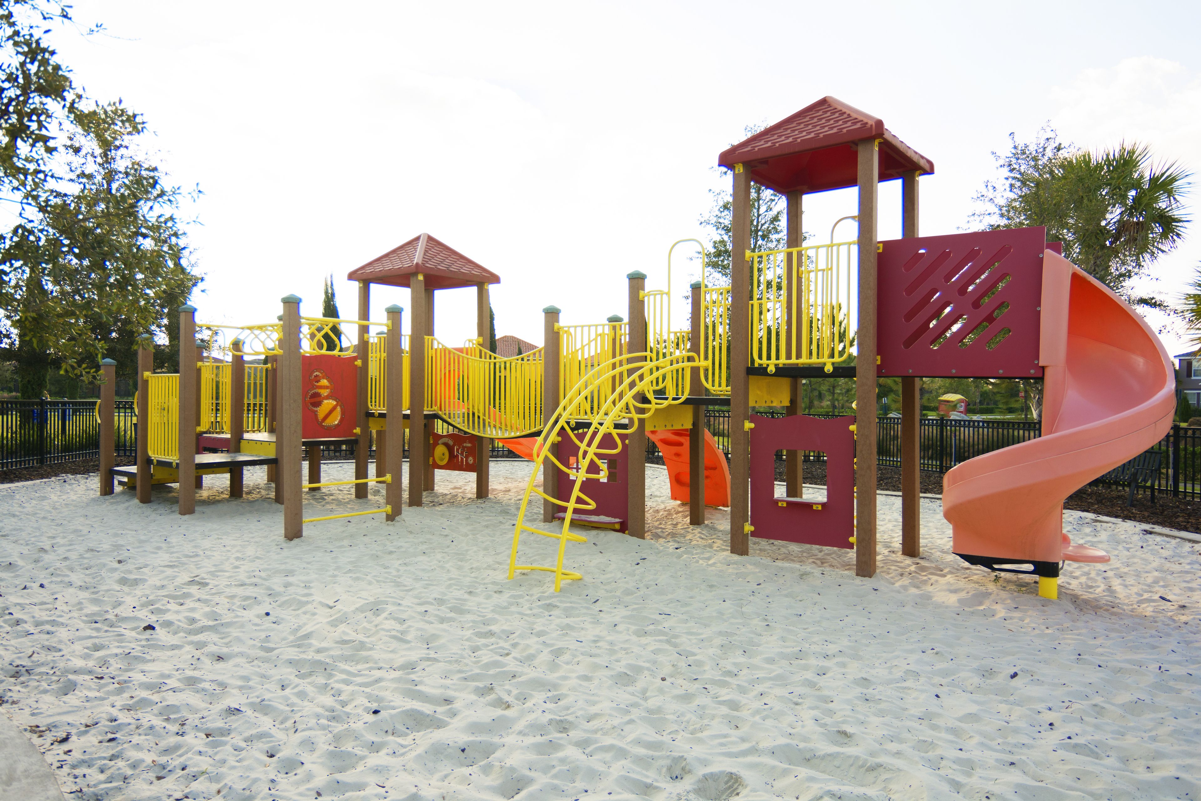 A playground with a slide, climbing structures, and a covered area.