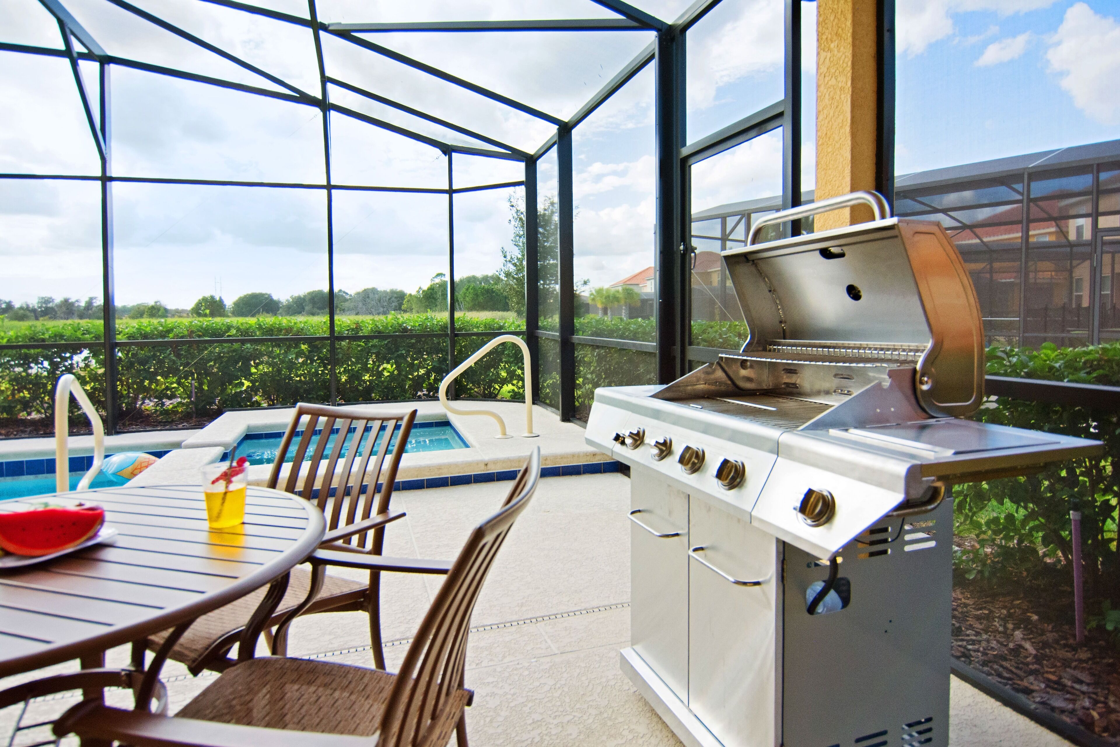 An outdoor patio with a grill, pool, and dining area.