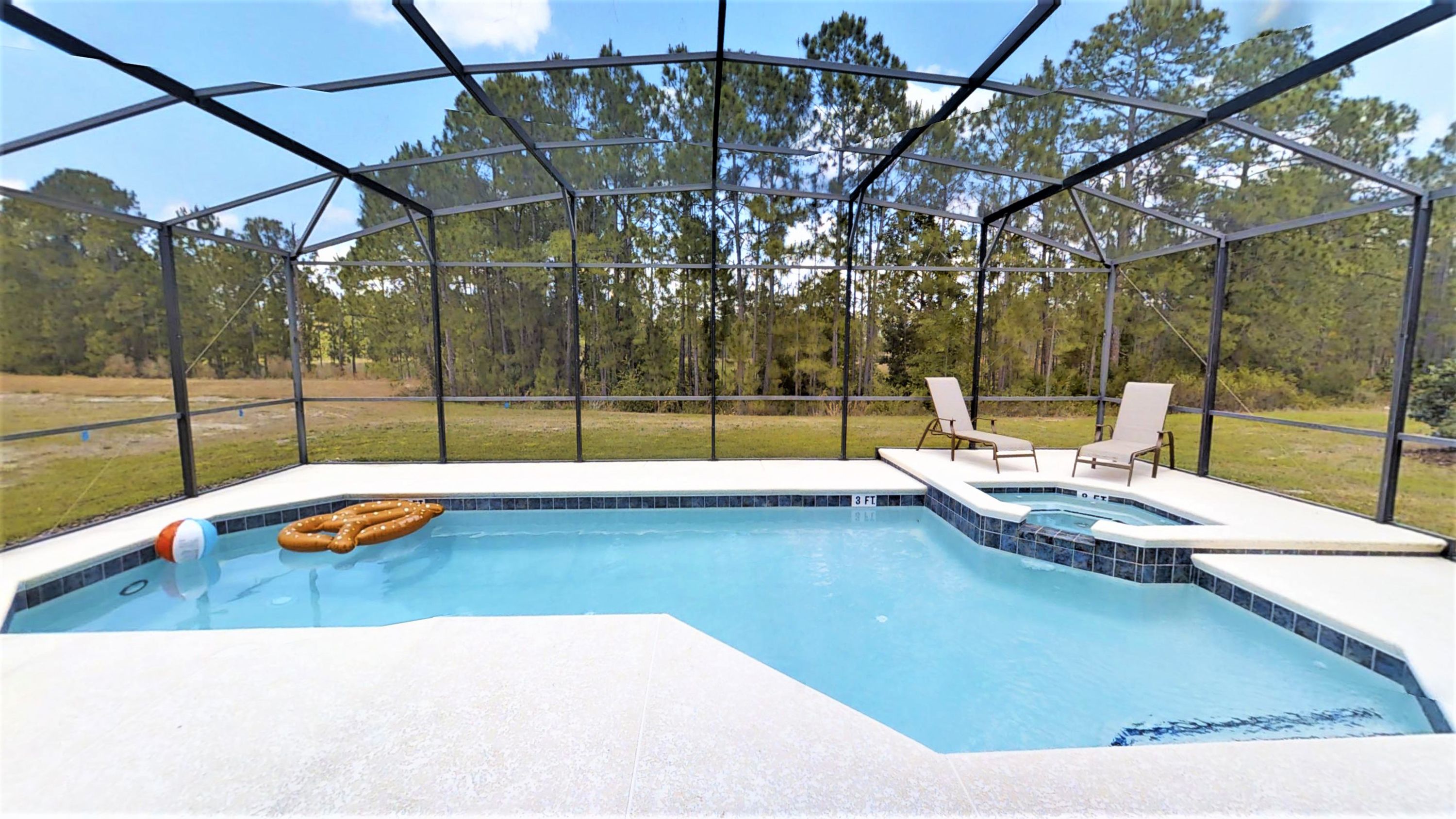 A swimming pool with a hot tub, surrounded by a covered area with chairs.